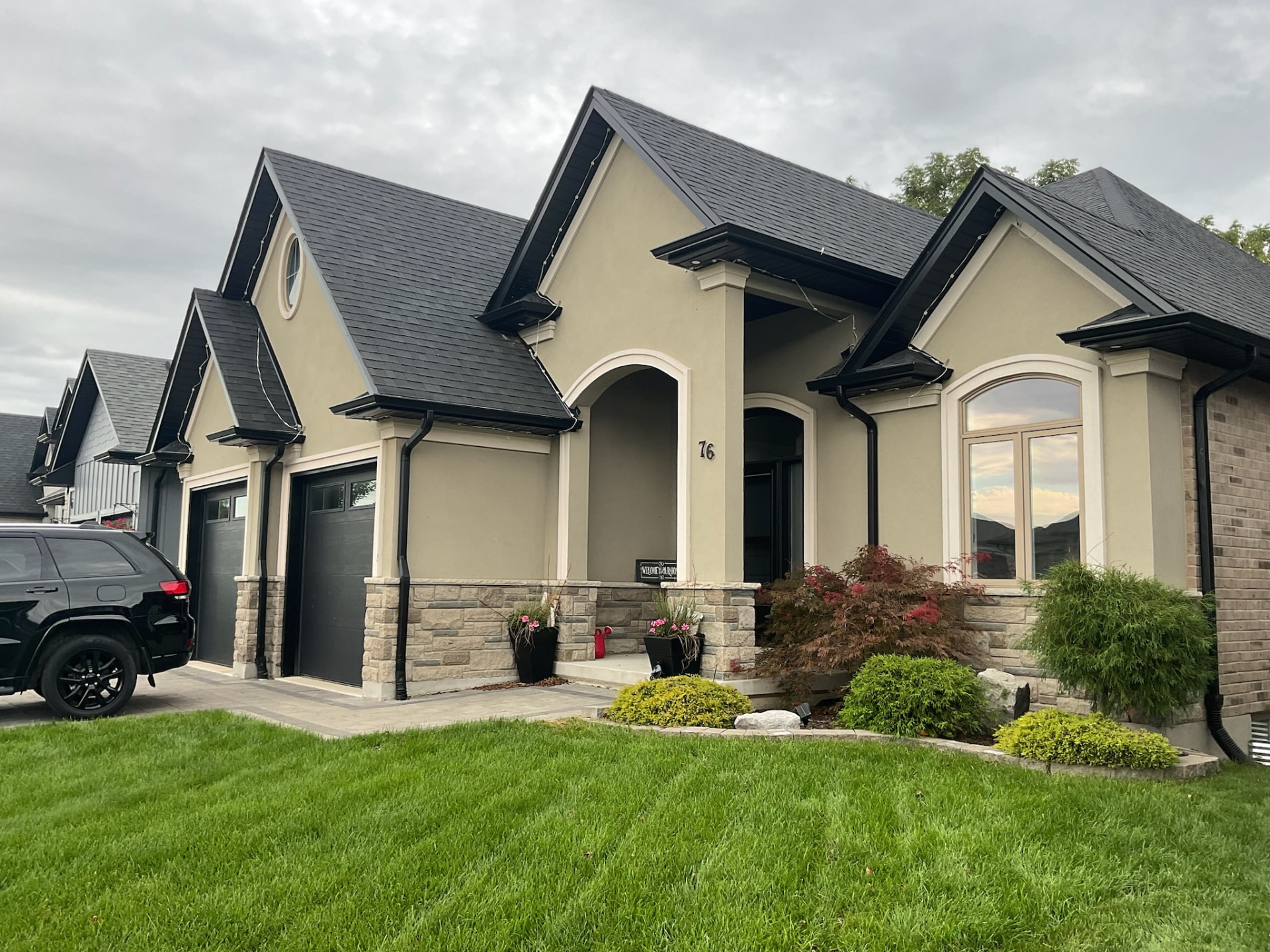 Beige and stone home with permanent roofline track installed across every gable