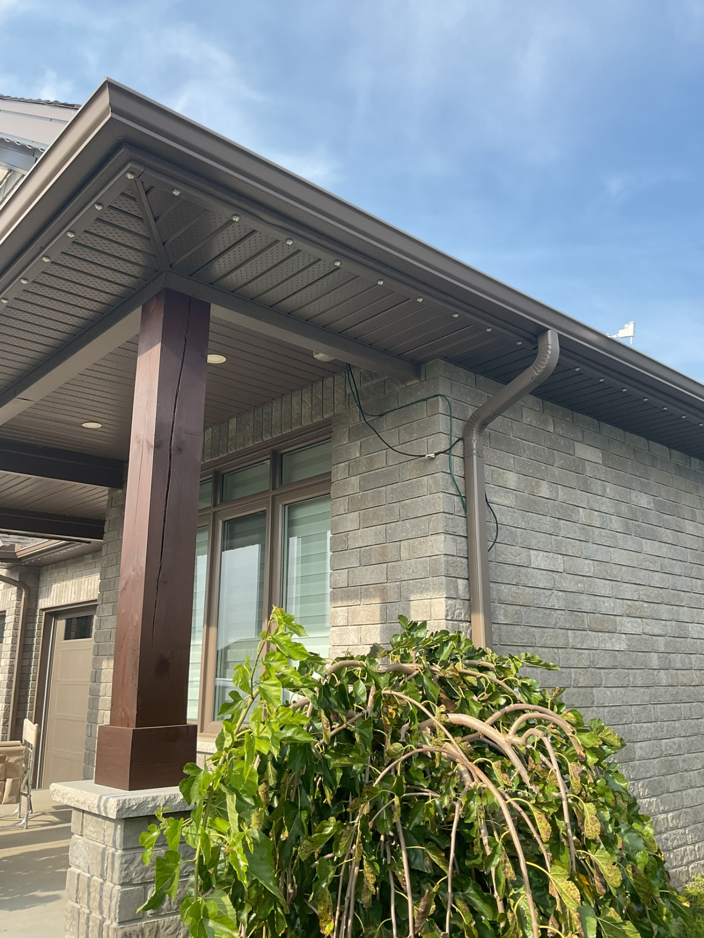 Permanent lighting track meeting a dark wood post on a brown soffit corner
