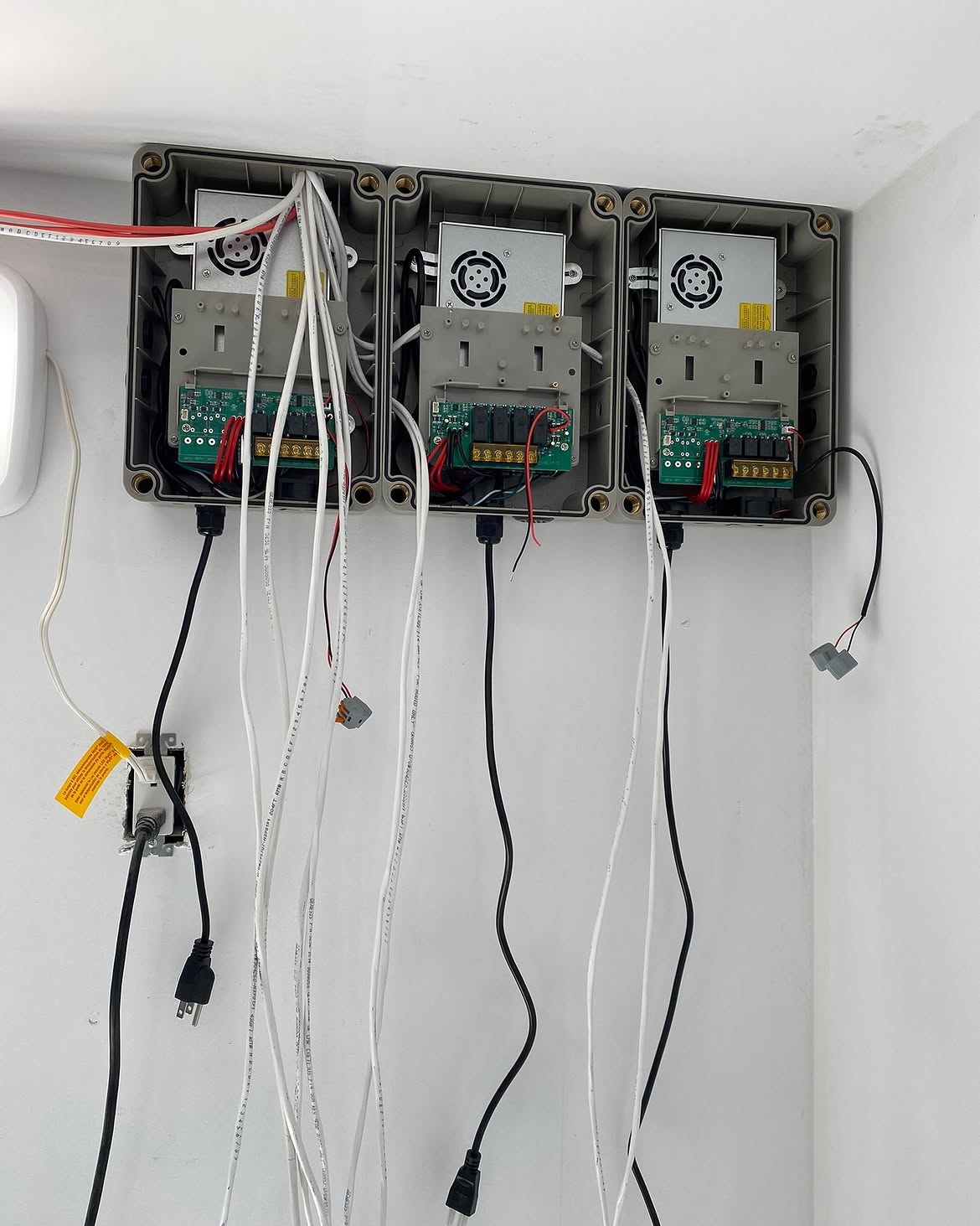 Three lighting controllers wired side by side in a garage