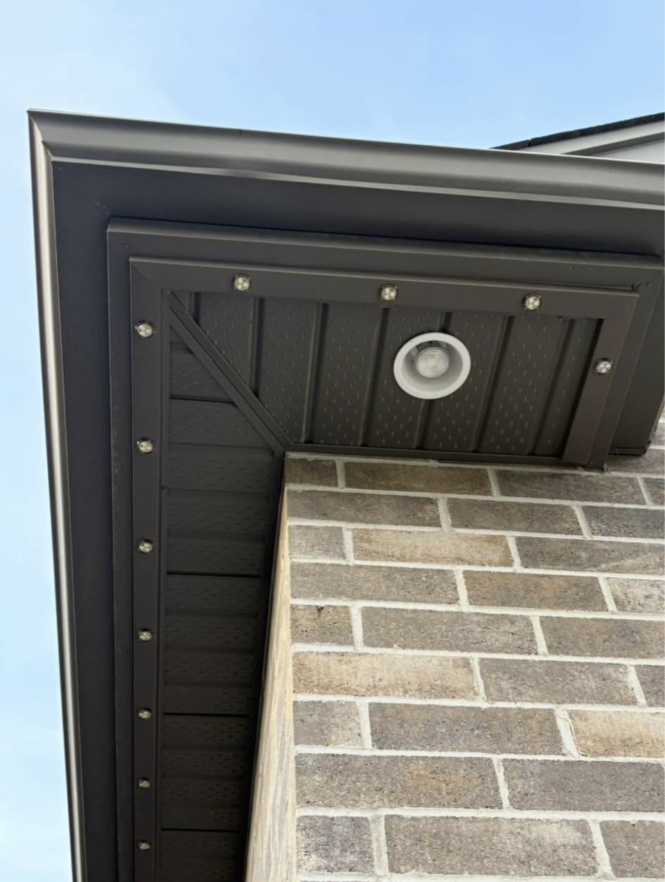Close-up of permanent lighting track on a brown soffit with recessed light