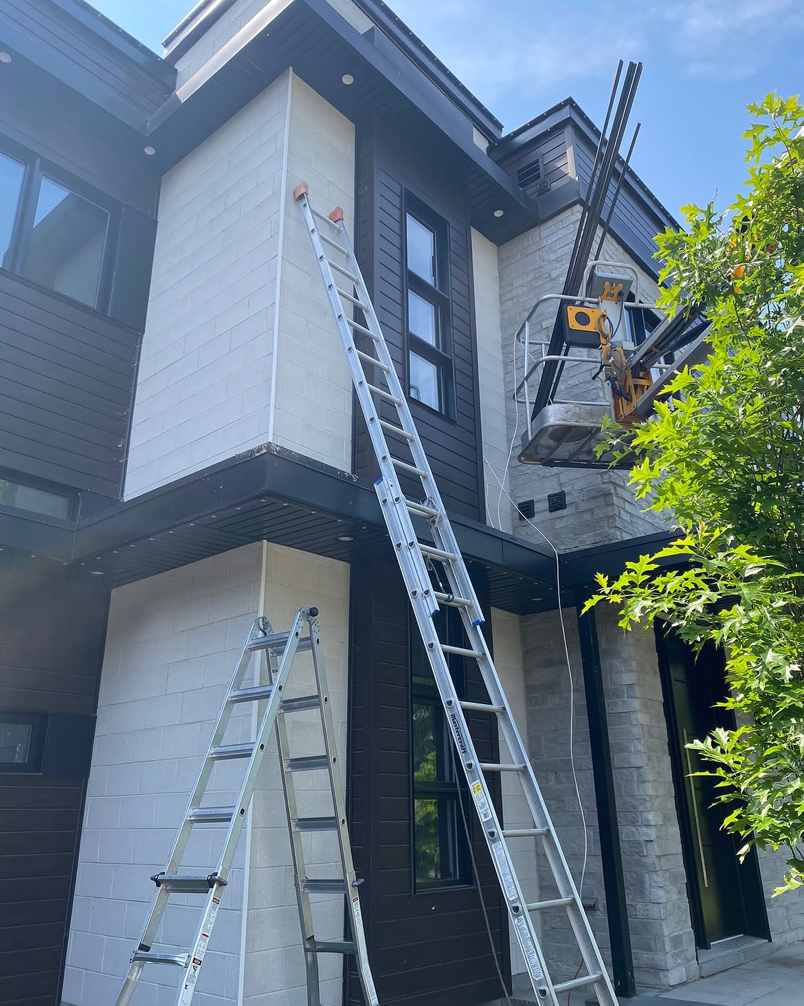 Ladders and a lift set up against a modern two-storey home during install