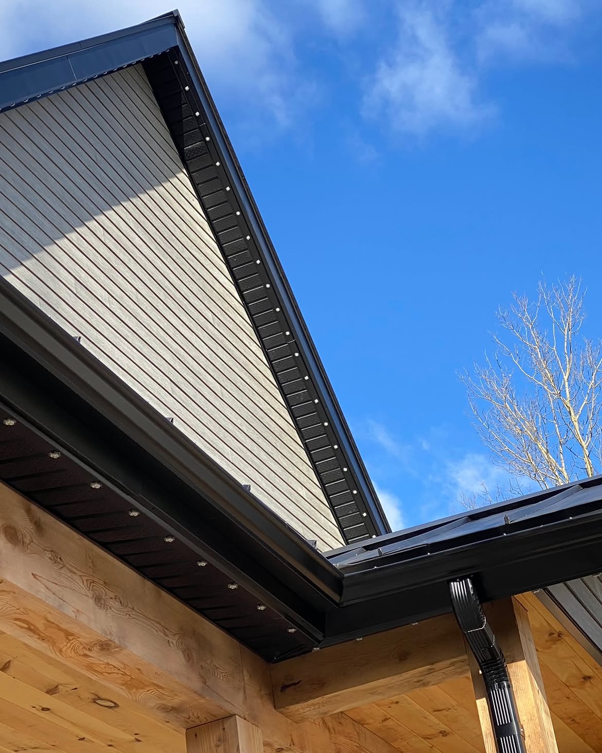 Permanent lighting track along a black roofline corner against blue sky