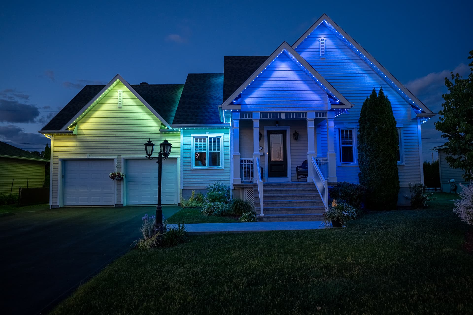 Home illuminated in blue, teal, and green permanent lighting