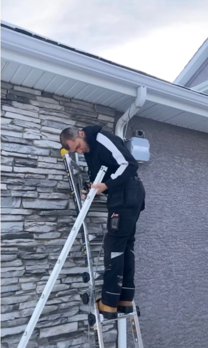 Installer on a ladder fitting track under an eave