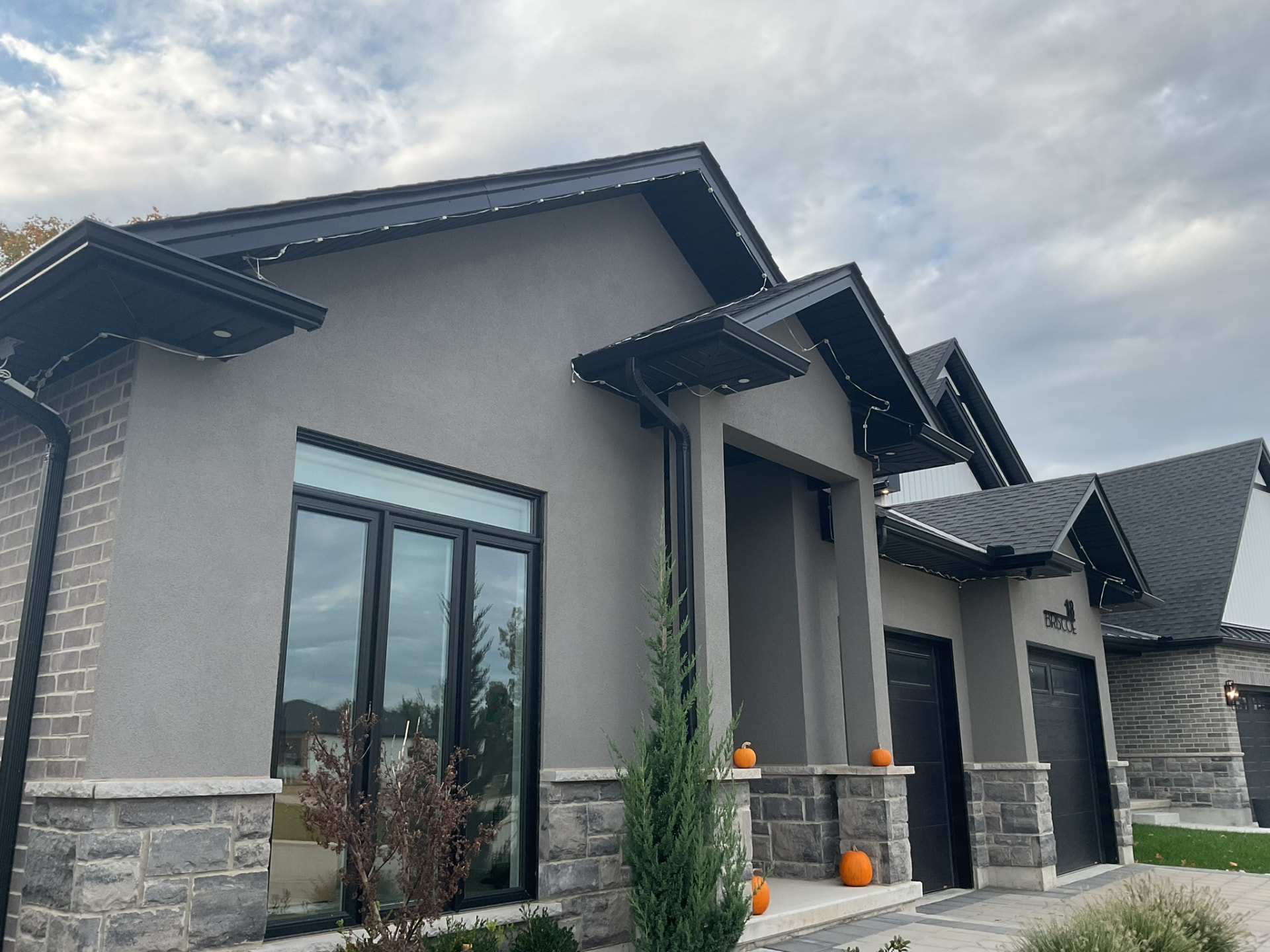 Grey stucco home with permanent lighting track along the eaves